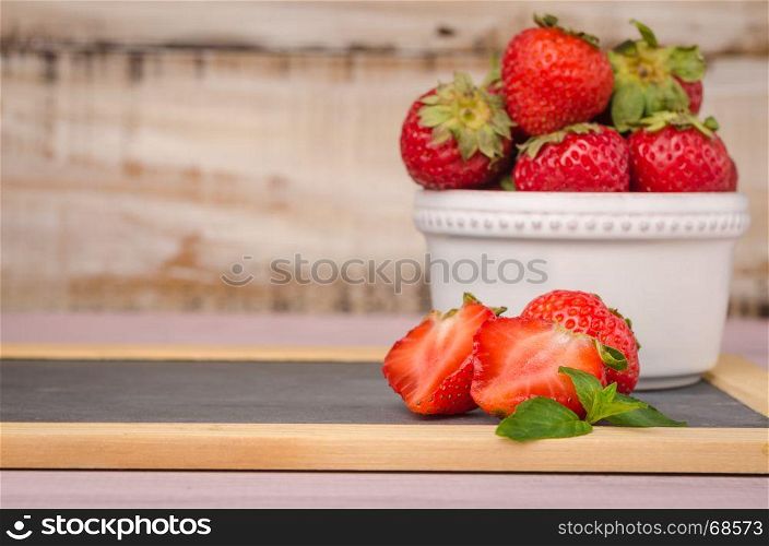 Fresh strawberries in bowl on slate.