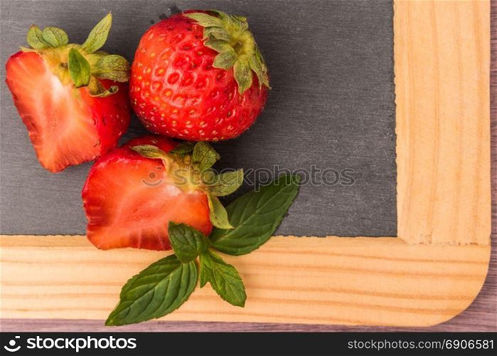 Fresh strawberries in bowl on slate. Top view with copy space