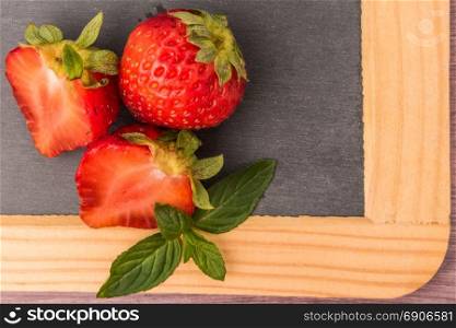 Fresh strawberries in bowl on slate. Top view with copy space