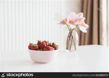 Fresh strawberries in bowl on white wooden table. Copy space