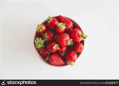 Fresh strawberries in bowl on white wooden table. Top view