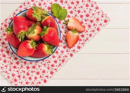 Fresh strawberries in bowl on wooden table. Top view with copy space