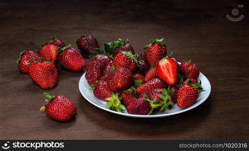 Fresh strawberries in ceramic bowl on dark wooden background. Selective focus. - Image