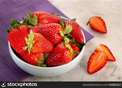 Fresh strawberries in ceramic bowl on white marble table