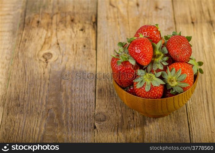 fresh strawberries in wood bowl on old wooden background