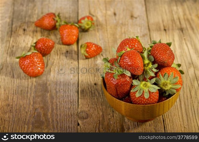 fresh strawberries in wood bowl on old wooden background