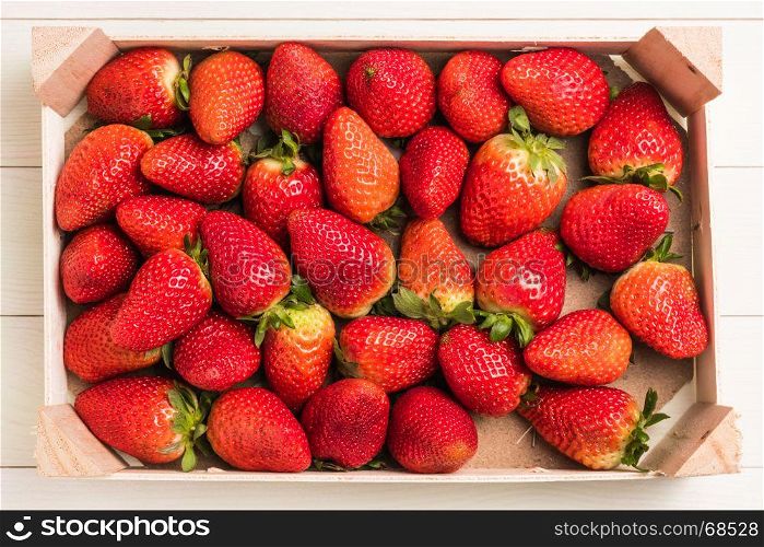 Fresh strawberries in wooden basket on wooden table. Top view with copy space