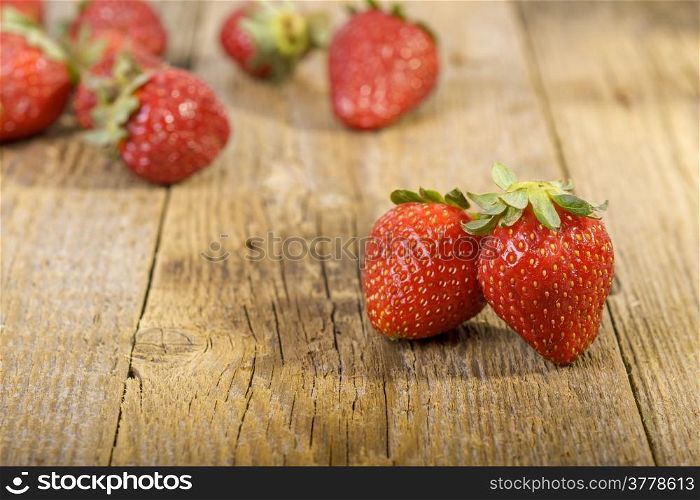 fresh strawberries on wooden table. focus on first two strawberries