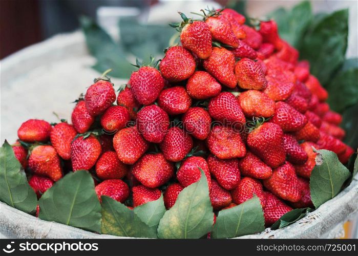 Fresh strawberries with green leaves in wooden baskets at the market