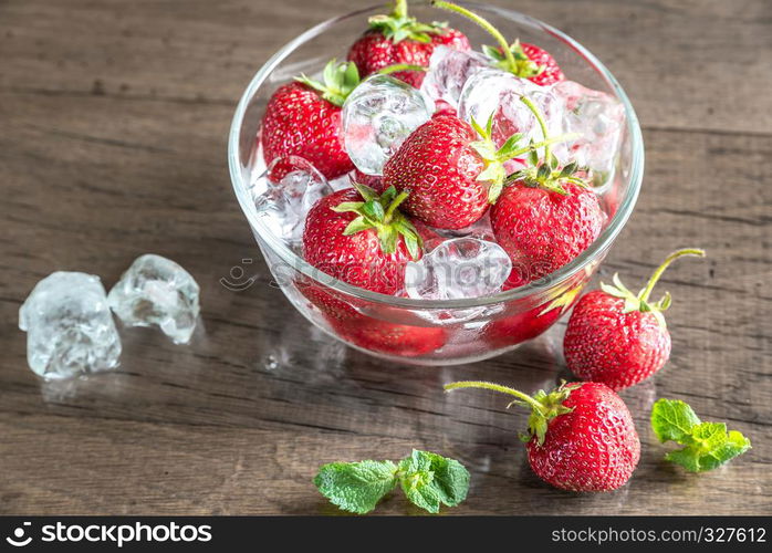 Fresh strawberries with ice cubes in the glass bowl