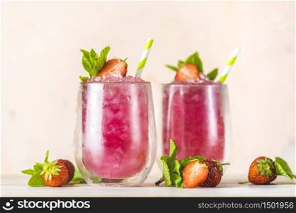 Fresh strawberry cocktail. Fresh summer cocktail with strawberry and ice cubes. Glass of strawberry soda drink on light pink background.