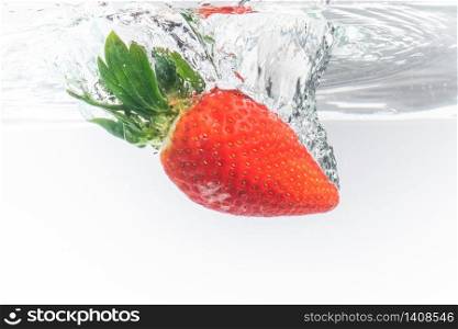 Fresh strawberry dropped into clear water with splash isolated on white background. Splash photography. Fresh strawberry dropped into clear water with splash isolated on white background.