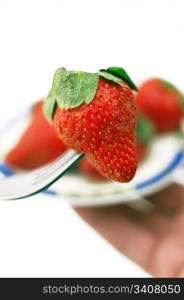 fresh strawberry on a fork over white