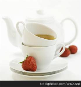 fresh strawberry, white teacup with hot tea and teapot on white background