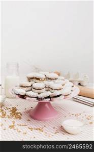 fresh sugary dessert stacked cake stand with ingredients against white wall