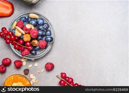 Fresh summer berries and nuts on gray stone background, top view. Healthy food and Clean Eating concept