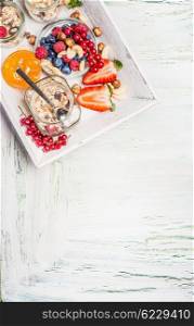 Fresh summer berries with muesli on white kitchen tray on shabby chic wooden background, top view,place for text. Healthy breakfast .
