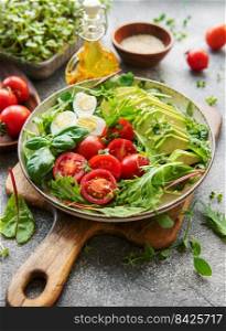 Fresh summer salad with arugula,  red cherry tomatoes, basil, eggs and avocado. Vegan food. Healthy salad
