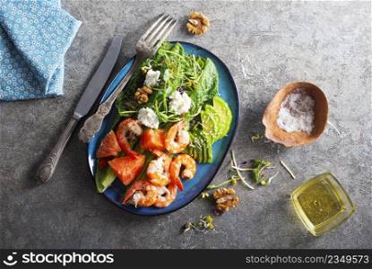 Fresh summer salad with shrimp, avocado and tomato in bowl on light table. Concept of healthy eating.