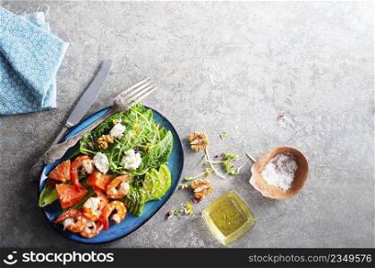 Fresh summer salad with shrimp, avocado and tomato in bowl on light table. Concept of healthy eating.