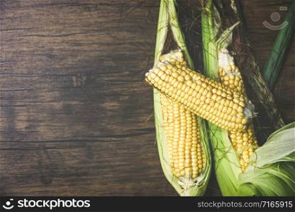 Fresh sweet corn ears on wooden background / Corn on cobs , top view copy space