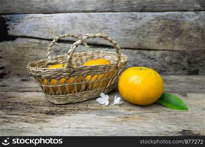 Fresh tangerines in a basket on grunge wooden background