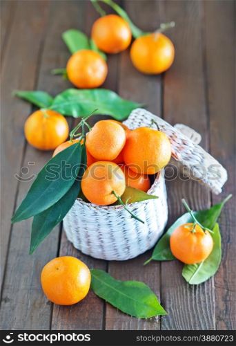 fresh tangerines in the white basket and on a table