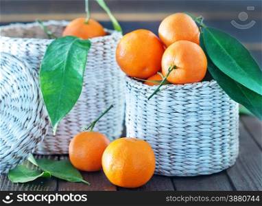 fresh tangerines in the white basket and on a table