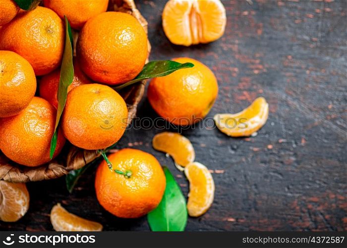 Fresh tangerines with leaves in a basket. Against a dark background. High quality photo. Fresh tangerines with leaves in a basket.