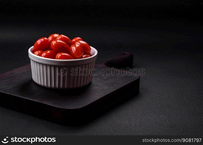 Fresh tasty cherry tomatoes in a white ribbed bowl on a dark concrete background