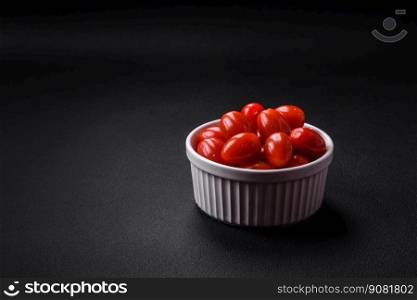 Fresh tasty cherry tomatoes in a white ribbed bowl on a dark concrete background