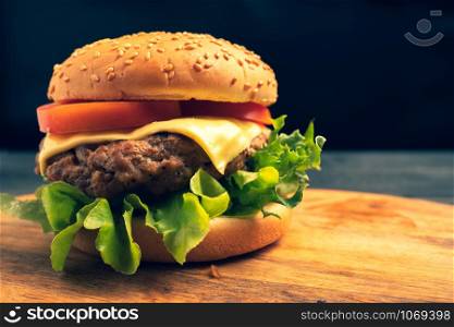 fresh tasty homemade hamburger with fresh vegetables, lettuce, tomato, cheese on a cutting board. Free space for text
