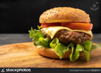 fresh tasty homemade hamburger with fresh vegetables, lettuce, tomato, cheese on a cutting board. Free space for text