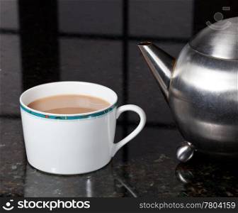 Fresh tea poured into white cup on marble kitchen worktop