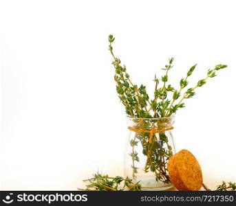 fresh thyme on a glass jar over a white wood rustic table