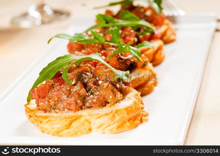 fresh tipycal italian bruschetta with tomato and arugula on top