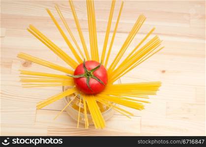 fresh tomato and raw spaghetti pasta over pine wood table
