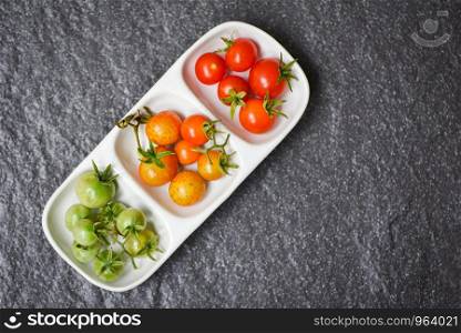Fresh tomato cherry organic / Green and ripe red tomatoes in cup with dark background - selective focus