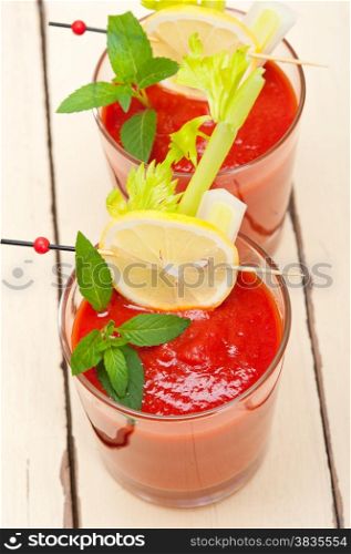 fresh tomato juice gazpacho soup on a glass over white wood table