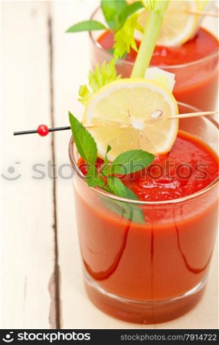 fresh tomato juice gazpacho soup on a glass over white wood table