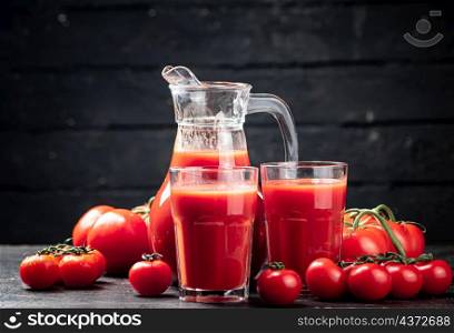 Fresh tomato juice in a jug. On a wooden background. High quality photo. Fresh tomato juice in a jug.