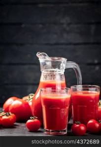 Fresh tomato juice in a jug. On a wooden background. High quality photo. Fresh tomato juice in a jug.