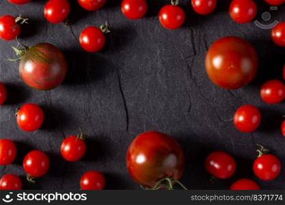 Fresh tomato on black slate background table. Tomatoes at tabletop top view
