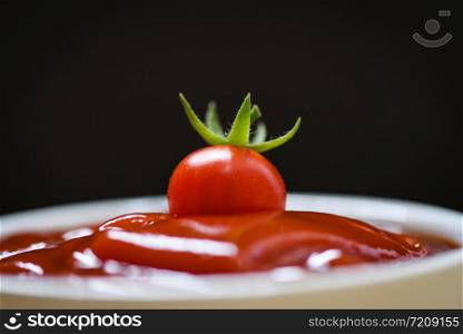 Fresh tomato on ketchup and dark background / Close up tomato sauce in cup - selective focus