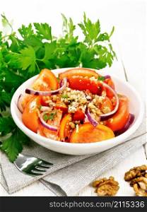 Fresh tomato salad with walnuts and red onions, seasoned with olive oil, vinegar, fenugreek and salt in a plate on a napkin on wooden board background