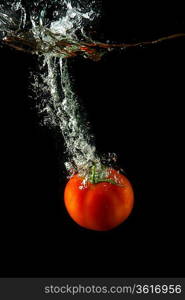 fresh tomato uder water on black background