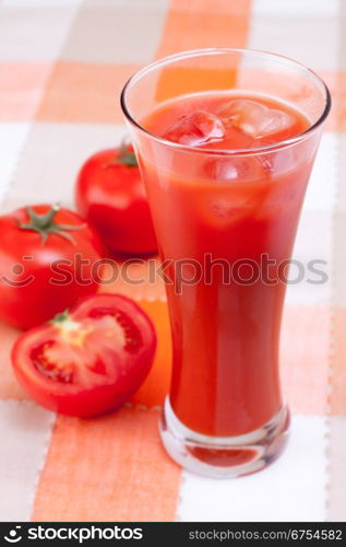 Fresh tomatoes and a glass full of tomato juice.