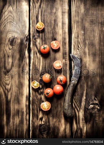 Fresh tomatoes and an old knife. On wooden background.. Fresh tomatoes and an old knife.