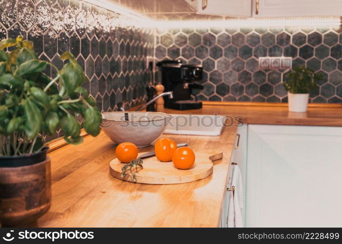 fresh tomatoes and basil in modern kitchen interior with white furniture home background