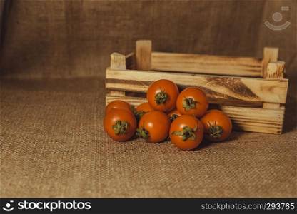 Fresh tomatoes and old burnt wooden crate or box with sackcloth background.Vintage and retro effect added.. Fresh tomatoes and old burnt wooden crate or box with sackcloth background.